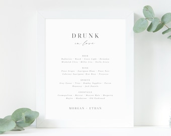 May include: A white framed sign with the text "DRUNK in love" at the top. The sign lists various alcoholic beverages, including beer, wine, spirits, and cocktails.