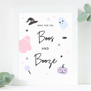 Puede incluir: Impresi&oacute;n enmarcada en blanco con el texto "Here for the boos and booze" en escritura negra. La impresi&oacute;n presenta un fantasma rosa, un sombrero de bruja negro, una piruleta morada, una calabaza morada y un murci&eacute;lago negro.