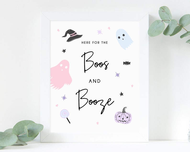 Puede incluir: Impresi&oacute;n enmarcada en blanco con el texto "Here for the boos and booze" en escritura negra. La impresi&oacute;n presenta un fantasma rosa, un sombrero de bruja negro, una piruleta morada, una calabaza morada y un murci&eacute;lago negro.