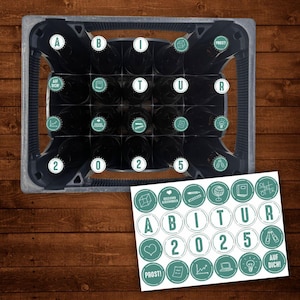 May include: A green and white sticker sheet with 16 round stickers featuring graduation-themed designs. The stickers include the words "Abitur 2025", "Prost!" and "Auf Dich!" along with icons like a graduation cap, a heart, a pencil, a globe, a book, a game controller, a laptop, a light bulb, and a pair of crossed champagne flutes.