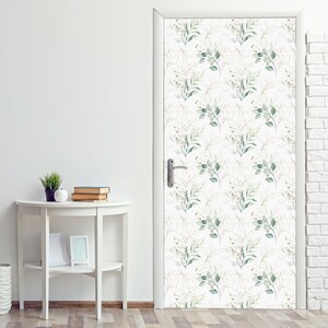 May include: A white door with a green and gold floral pattern. The pattern features small green leaves and branches with gold accents.