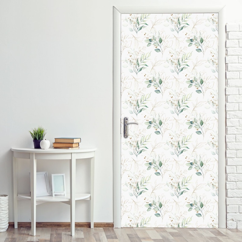 May include: A white door with a green and gold floral pattern. The pattern features small green leaves and branches with gold accents.