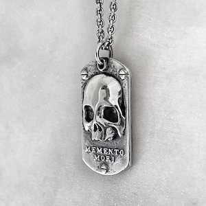side view of silver dog tag featuring a skull and the words memento mori by jewel thief brighton