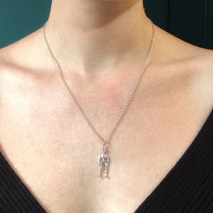 May include: A silver chain necklace with a silver skeleton pendant.