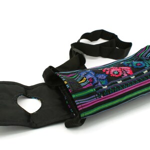 May include: A black and colorful fabric water bottle holder with an adjustable strap. The holder has a heart-shaped opening for easy access to the bottle.