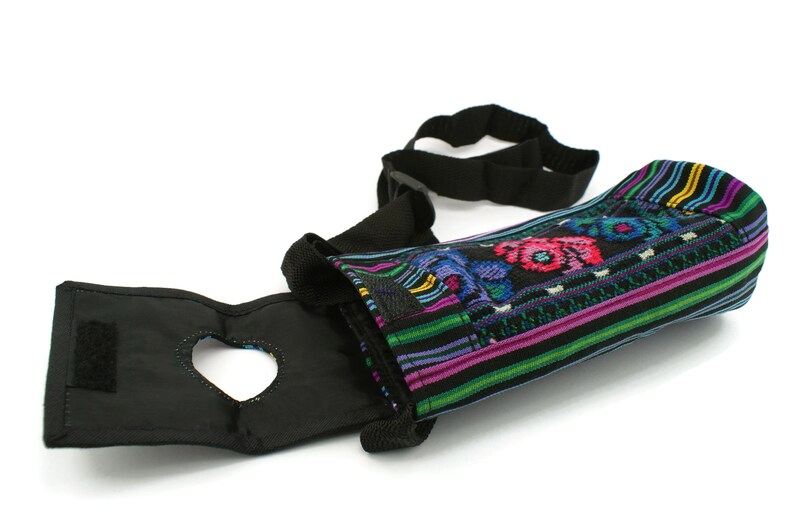 May include: A black and colorful fabric water bottle holder with an adjustable strap. The holder has a heart-shaped opening for easy access to the bottle.