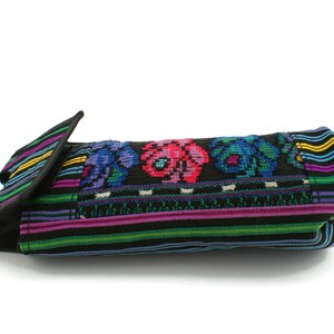 May include: A black fabric bag with a colorful embroidered floral design. The bag has a flap that folds over and closes with a snap.