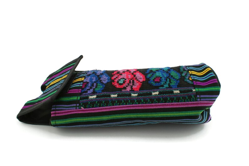 May include: A black fabric bag with a colorful embroidered floral design. The bag has a flap that folds over and closes with a snap.