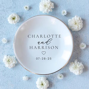 Personalized ceramic ring dish with custom names and date — engagement gift, wedding gift, bridesmaid gift, jewelry holder tray.

Custom round jewelry dish with heart accent and names and date — personalized engagement gift for bride-to-be

White ceramic trinket dish for rings and jewelry — personalized names ring dish for bridal shower or proposal gift

Engagement ring holder dish with custom lettering — wedding keepsake gift for couples, bride, or bridesmaids