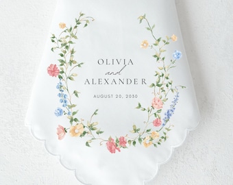 May include: White wedding handkerchief with a floral wreath design in shades of pink, blue, and yellow. The text "Olivia and Alexander" and "August 20, 2030" is printed in black.