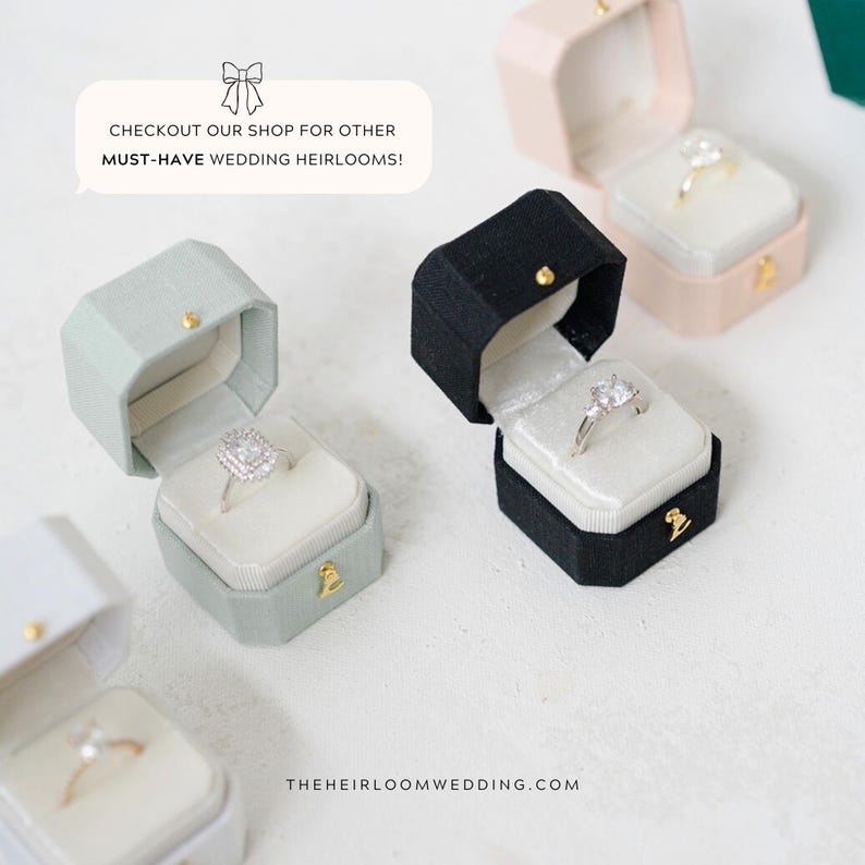 May include: Several open ring boxes in various colors, including black, pink, and green, each displaying a different engagement ring. The boxes are octagonal and lined with white velvet. Text in the image reads: "CHECKOUT OUR SHOP FOR OTHER MUST-HAVE WEDDING HEIRLOOMS!"