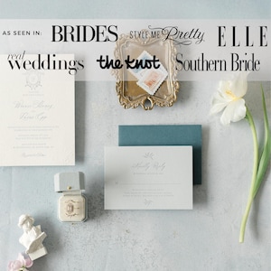 May include: A collection of wedding stationery, including an invitation, reply card, and envelope in pastel shades. A ring box and a small sculpture are also visible. The image includes text from wedding publications.