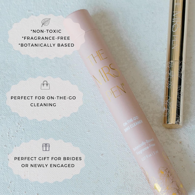 K&ouml;nnte beinhalten: Eine rosa und goldene Tube mit dem Text "The Mrs. Pen" und "On-the-Go Ring Cleaner". Die Tube ist als ungiftig, parf&uuml;mfrei und auf pflanzlicher Basis gekennzeichnet. Die Tube befindet sich neben einem goldenen Stift mit dem Text "The Mrs. Pen".