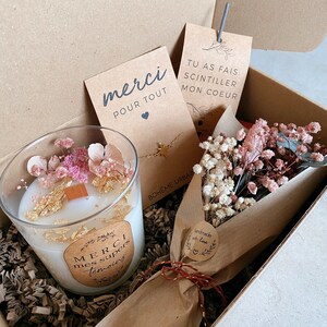 May include: A gift box filled with a white candle with dried flowers and gold flakes, a small bouquet of dried flowers wrapped in brown paper, a gold necklace with a star charm, and two cards. One card says "merci pour tout" and the other says "tu as fais scintiller mon coeur".