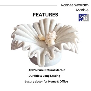May include: White marble decorative bowl with a ruffled edge, featuring a flower-like design. The bowl is made of 100% pure natural marble and is durable and long-lasting. It is a luxury decor piece for home and office.
