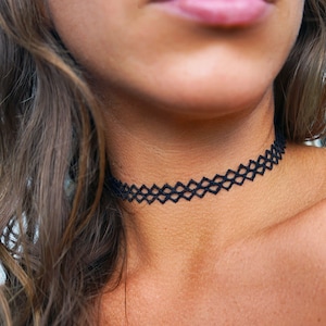 May include: A black choker necklace with a diamond-shaped pattern.