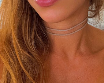 May include: A double-layered suede choker necklace in a light beige color.