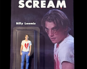 May include: A Scream action figure of Billy Loomis in a plastic blister pack. The figure is wearing a white t-shirt with a red heart design and blue jeans. The packaging features the word "SCREAM" in large white letters and an image of a man.