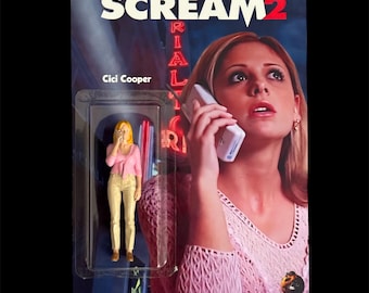 May include: A Scream 2 action figure of Cici Cooper in a plastic blister pack. The packaging features the movie title and a photo of a woman on the phone. The figure is wearing a pink top and tan pants.