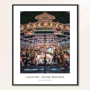 May include: A framed print of a carousel at Crescent Park in Riverside, Rhode Island. The carousel features ornate horses in various colors, with the word "ENTRANCE" displayed above. The print is by Wolf Matthewson.