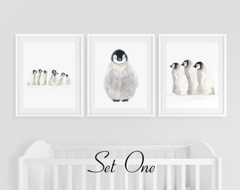 May include: Set of three watercolor penguin prints in white frames. The prints feature a group of penguins, a single penguin, and three penguins standing together.