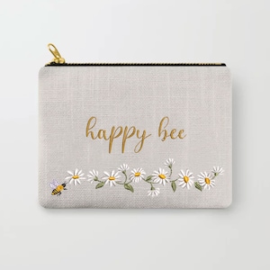 May include: A gray zippered pouch with a white daisy chain and a bee embroidered on it. The text "happy bee" is embroidered in gold on the pouch.