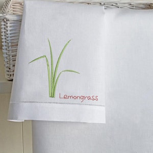 Puede incluir: Toalla de cocina blanca con citronela bordada en verde y la palabra "Lemongrass" en bordado rojo.