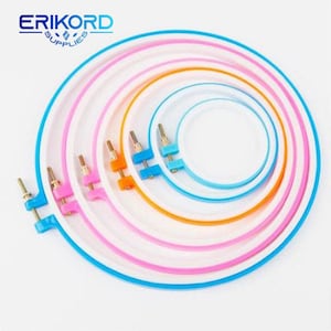 Puede incluir: Un conjunto de seis bastidores de bordado de diferentes tamaños. Los bastidores están hechos de plástico y tienen una base blanca con un borde azul, rosa o naranja. Los bastidores están anidados uno dentro del otro, con el bastidor más grande en la parte inferior y el más pequeño en la parte superior.