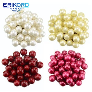 May include: Four piles of pearl-like decorative balls. One pile is white, one is cream, one is red, and one is pink.