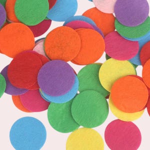 Op de afbeelding: Assortiment van kleurrijke vilt cirkels in verschillende tinten rood, oranje, geel, groen, blauw, paars en roze. De cirkels zijn verspreid over een witte achtergrond.