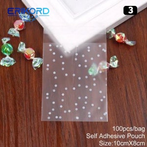 May include: A pack of 100 clear self-adhesive pouches with a white polka dot pattern. The pouches are 10cm x 8cm and are ideal for packaging small gifts or treats.