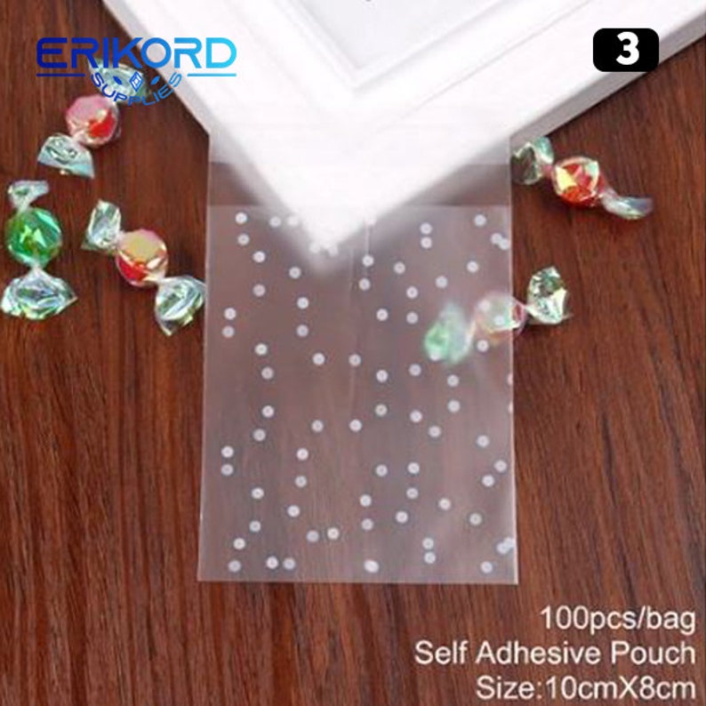 May include: A pack of 100 clear self-adhesive pouches with a white polka dot pattern. The pouches are 10cm x 8cm and are ideal for packaging small gifts or treats.