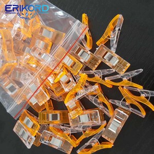 May include: A bag of clear plastic clips with orange accents. The clips are designed for sewing and quilting.