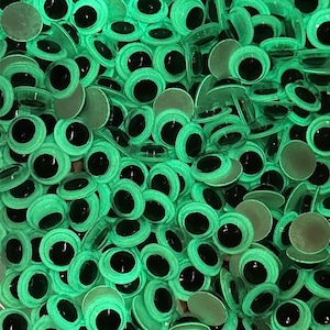 May include: A large pile of green googly eyes with black pupils. The eyes are plastic and have a shiny finish.