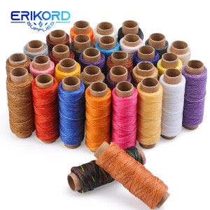 Puede incluir: Una colección de 25 carretes de hilo encerado en varios colores, incluyendo marrón, rojo, azul, naranja, rosa, amarillo, blanco y morado. Los carretes están dispuestos en un semicírculo con dos carretes en primer plano. Los carretes están hechos de cartón y tienen una etiqueta blanca con texto negro. El texto de la etiqueta dice "ERIKORD SUPPLIES".