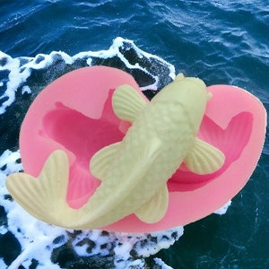 Puede incluir: Molde de silicona rosa para hacer un pastel o jabón en forma de pez blanco. El molde tiene forma de corazón y presenta un diseño de pez detallado.