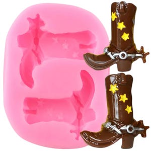 Puede incluir: Molde de silicona rosa con dos impresiones de botas de vaquero. Las botas son marrones con estrellas amarillas y una hebilla plateada.