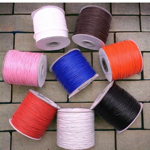 May include: Eight spools of waxed cord in various colors, including white, brown, pink, blue, red, black, and cream. The spools are arranged in a circle on a brick surface.