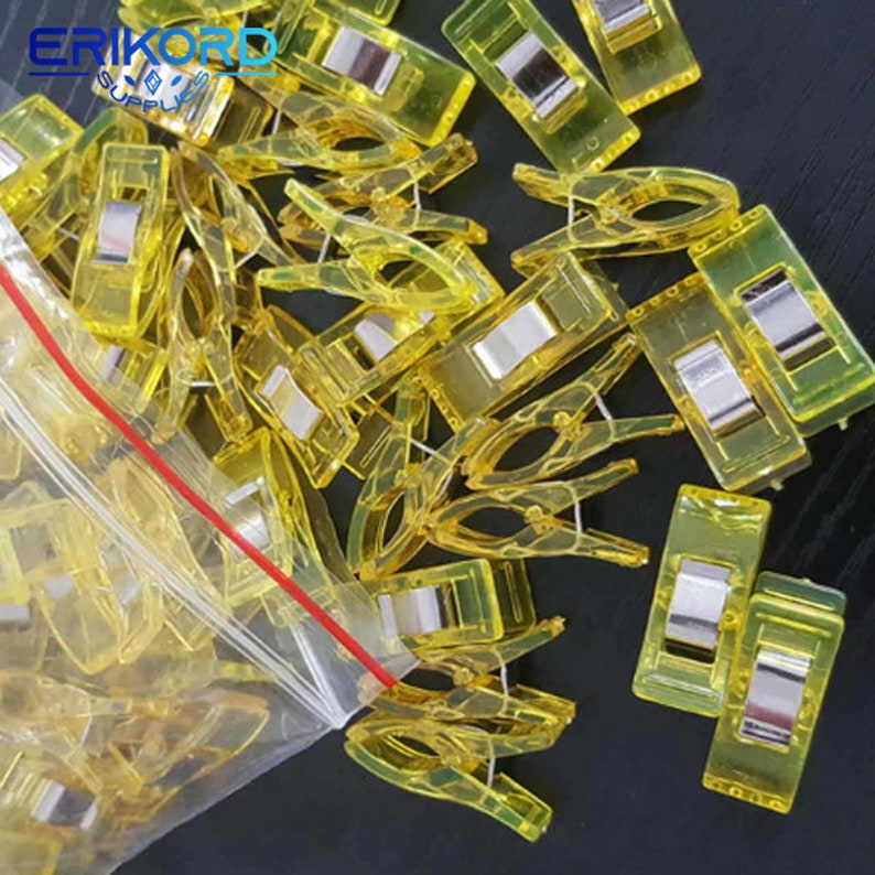 May include: A bag of yellow plastic clips with metal spring closures. The clips are used for holding fabric together while sewing.