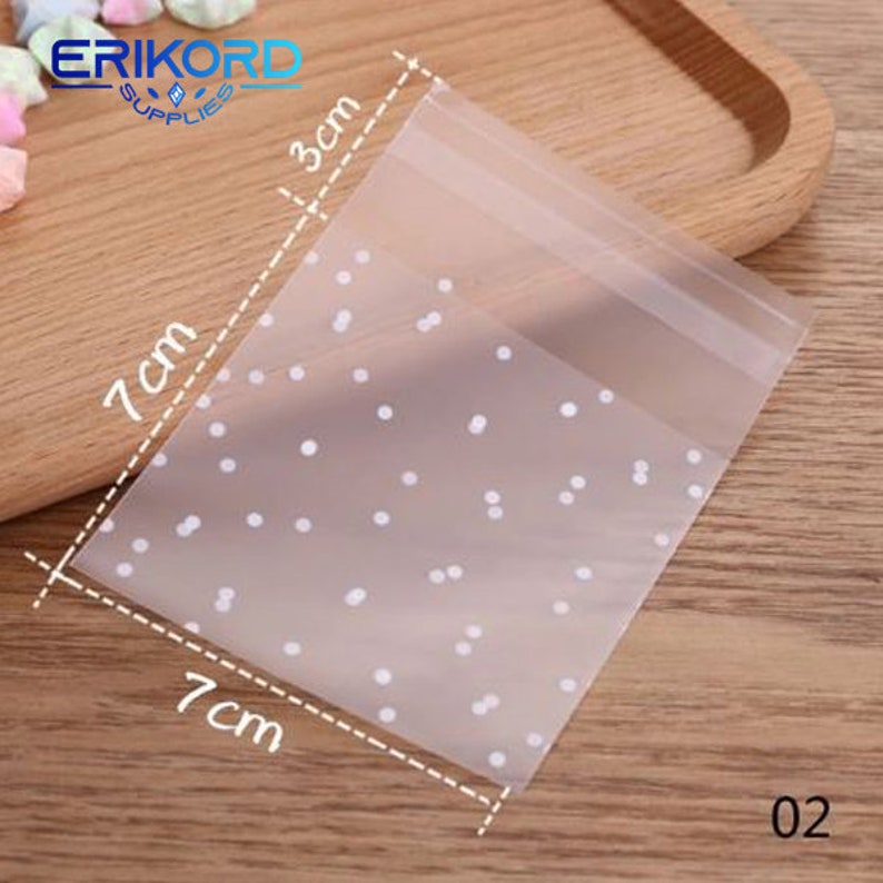 May include: Clear plastic bag with a white polka dot pattern. The bag measures 7 inches by 7 inches and 3 inches tall.
