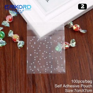 May include: 100 clear self-adhesive pouches with a white polka dot pattern. The pouches are 7 inches by 7 inches and are ideal for packaging small gifts or treats.