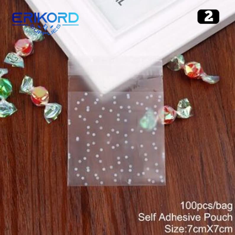 May include: 100 clear self-adhesive pouches with a white polka dot pattern. The pouches are 7 inches by 7 inches and are ideal for packaging small gifts or treats.