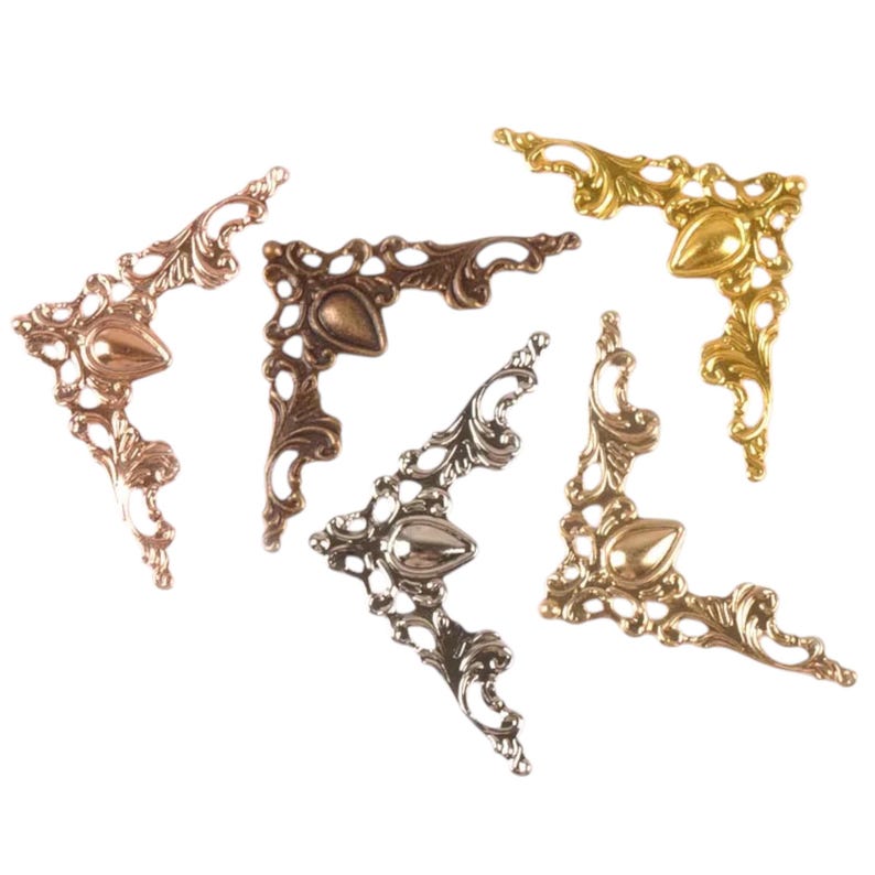 Pu&ograve; includere: Quattro angoli in metallo decorativi in finiture oro, argento e rame. Ogni angolo presenta un design decorativo e intricato con un centro a forma di goccia appuntita.