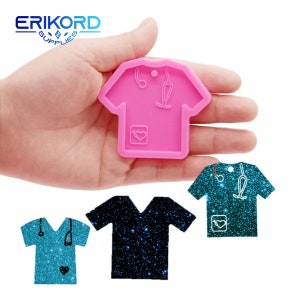 May include: Pink silicone mould shaped like a scrub top with a stethoscope, heart, and pocket. Two finished scrub top charms are shown, one blue and one teal with glitter.