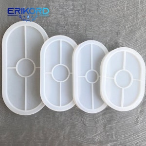 May include: Four white oval silicone molds of varying sizes. Each mold features a central circle and a cross-shaped design within the oval. The molds are arranged from largest to smallest, showcasing a range of sizes for crafting projects.