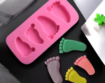 May include: Pink silicone mold with four baby foot shapes. Five finished baby foot shapes in green, purple, pink, and yellow.