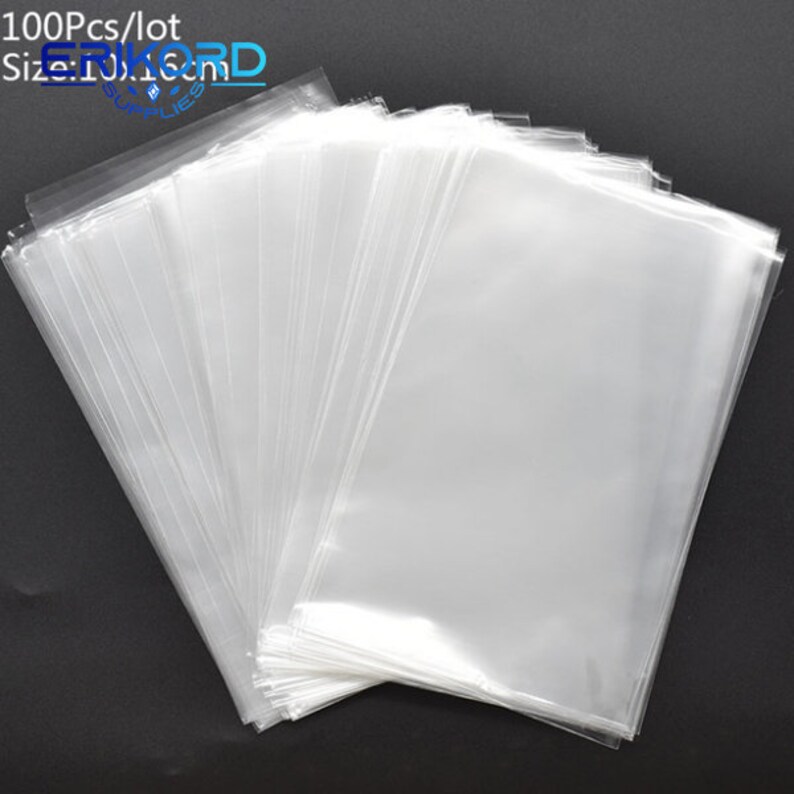 Op de afbeelding: Een stapel van 100 doorzichtige plastic zakjes, perfect voor het verpakken van kleine items. De zakjes zijn plat en hebben een gladde, glanzende afwerking.