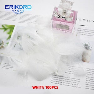 May include: A pile of 100 white feathers, ideal for crafting or decorating. The feathers are soft and fluffy, and they would be a great addition to any project.