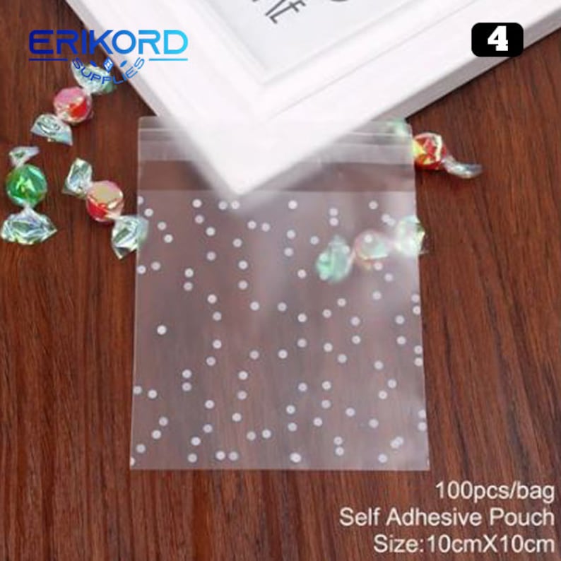 May include: A pack of 100 clear self-adhesive pouches with a white polka dot pattern. The pouches are 10 cm by 10 cm and are ideal for packaging small gifts or treats.