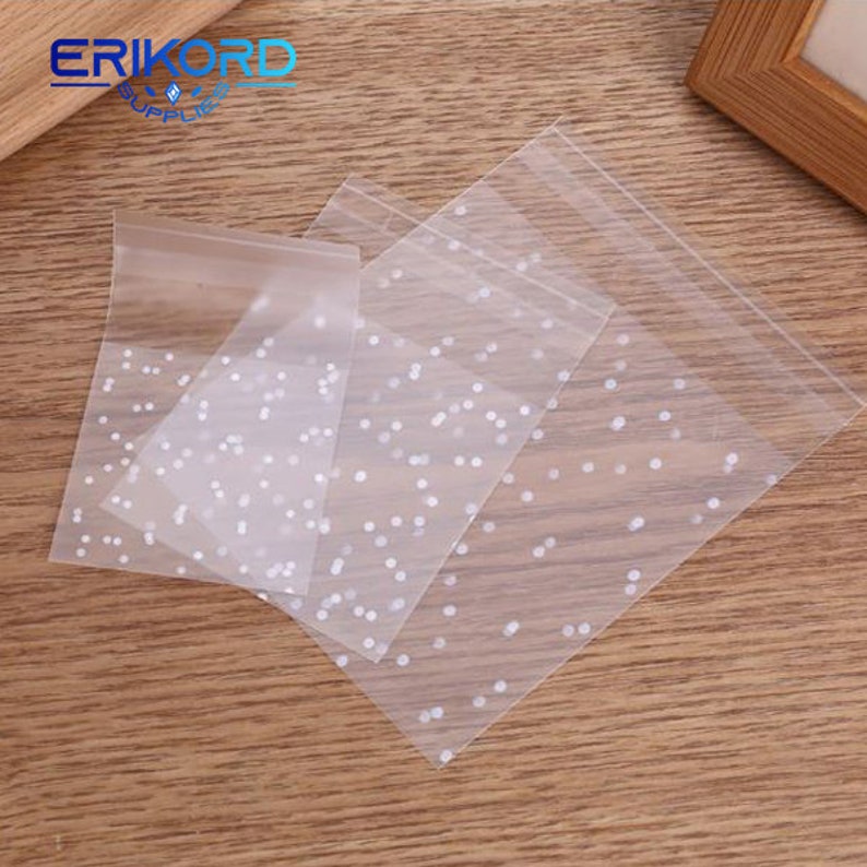 May include: Four clear plastic bags with white polka dots. The bags are stacked on top of each other.